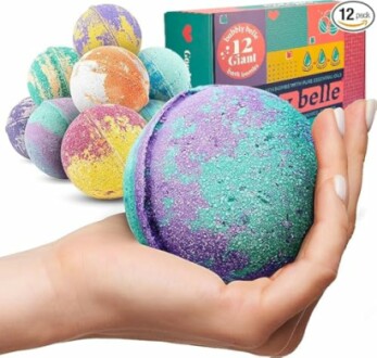 Hand holding colorful bath bomb with packaging and more bath bombs in background.