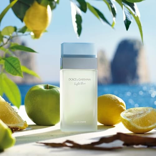 Dolce & Gabbana Light Blue perfume bottle with lemons and apples by the sea