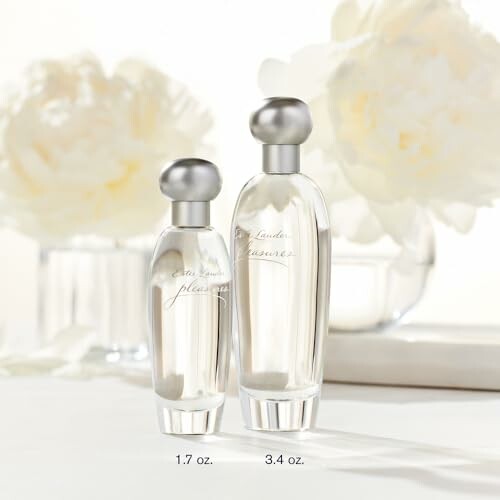 Two Estee Lauder Pleasures perfume bottles with flowers in the background.