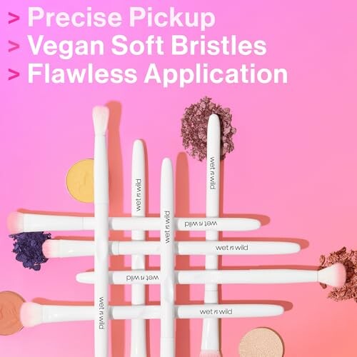 Makeup brushes with colorful powders on a pink background.