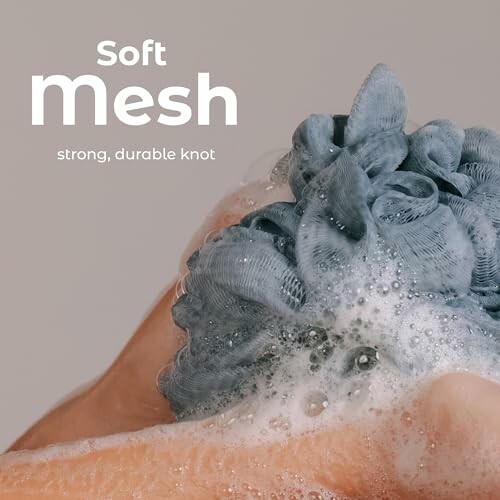 Person using a soft mesh bath sponge with suds