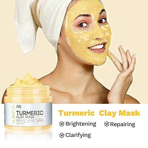 Woman applying turmeric clay mask to face.