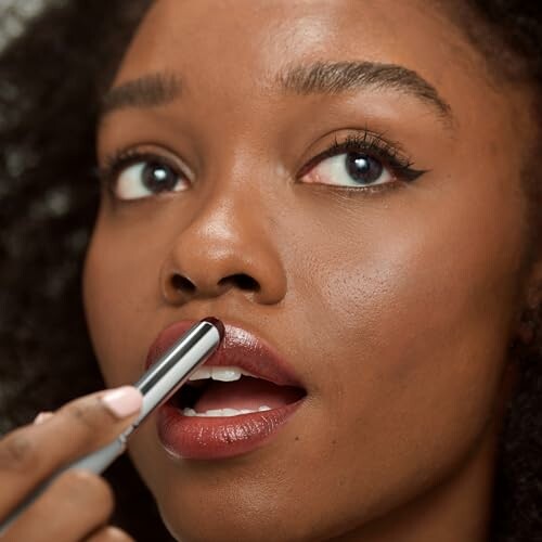 Woman applying lipstick to her lips