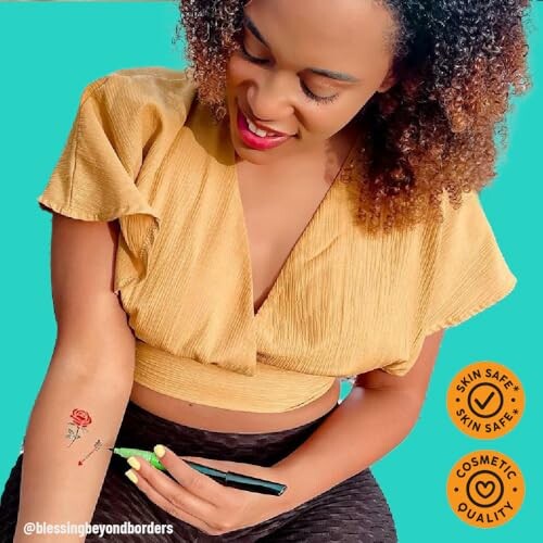 Woman using a pen to draw a flower tattoo on her arm.