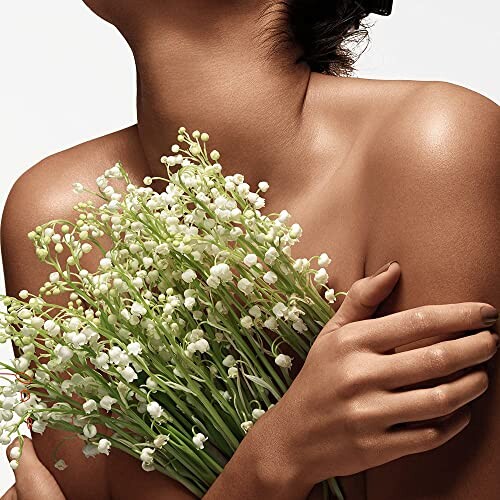 Woman holding bouquet of lily of the valley flowers against bare skin